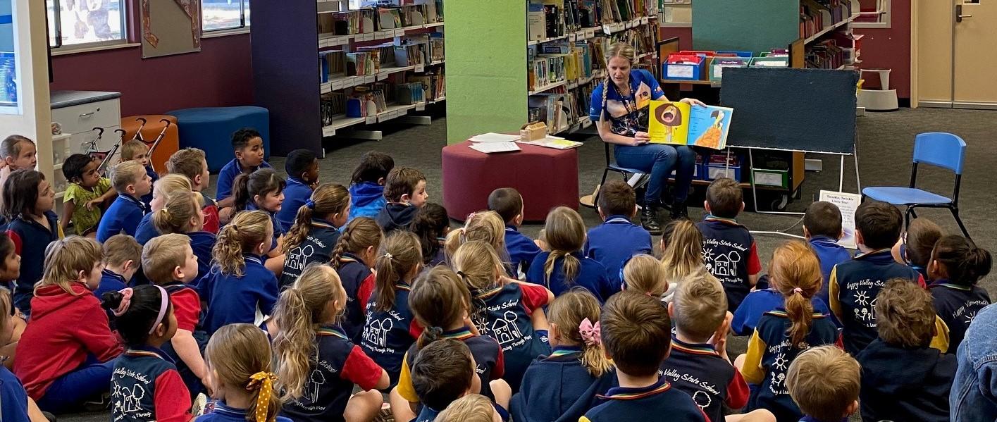 a teacher reading a book to kids in an outreach program